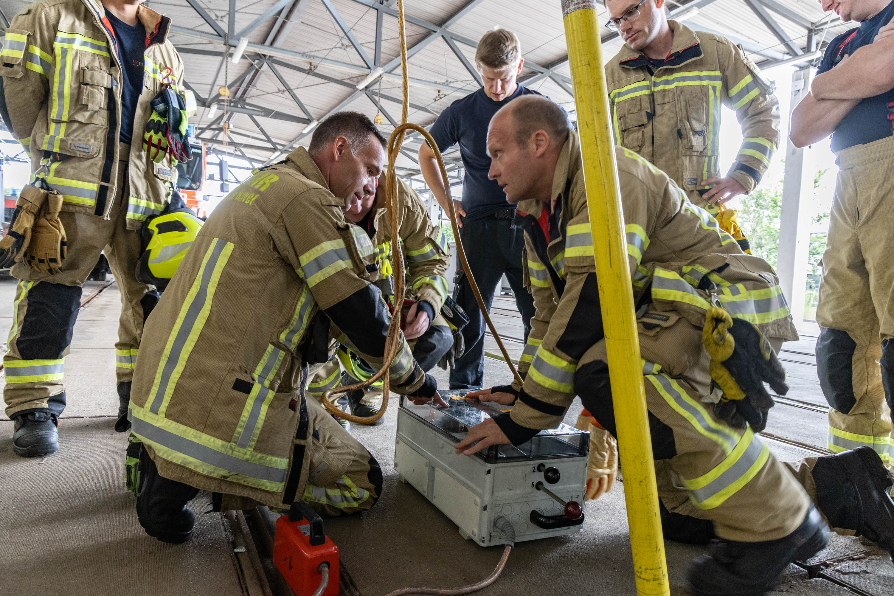 mehrere am Workshop teilnehmende Feuerwehrleute knien um das Erdungs- und Kurzschlussger&auml;t